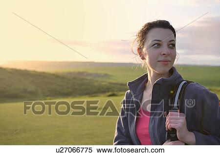 Stock Photography - Young female hiker looking over her shoulder. Fotosearch
