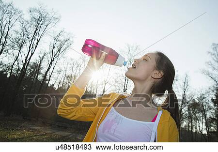 Stock Image - Young female runner drinking water. Fotosearch