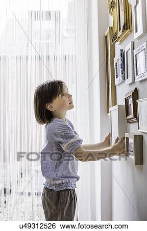 Young girl adjusting picture on wall View Large Photo Image Stock Photograph - Young girl adjusting picture on wall. Fotosearch
