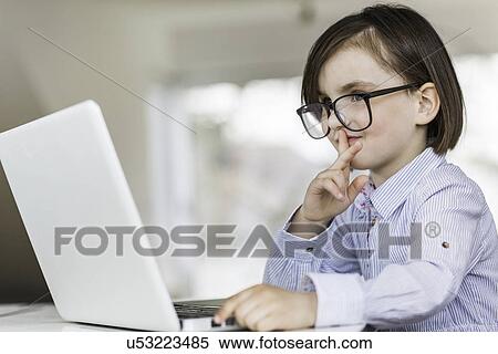 Stock Photography - Young girl wearing glasses using laptop. Fotosearch