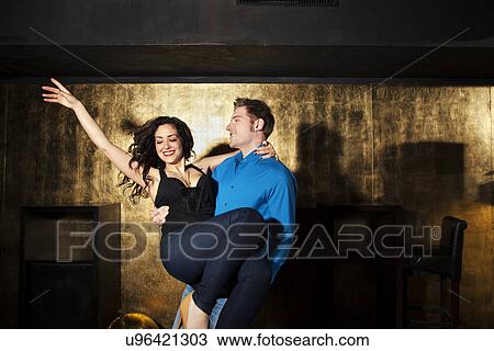 Young man dancing and carrying young woman in nightclub View Large Photo Image Stock Image - Young man dancing and carrying young woman in nightclub. Fotosearch