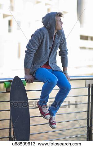 Stock Image - Young man gazing from riverside railings. Fotosearch