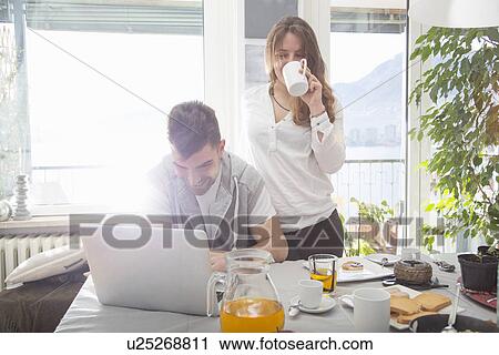 Young man having breakfast and using laptop View Large Photo Image Stock Image - Young man having breakfast and using laptop. Fotosearch