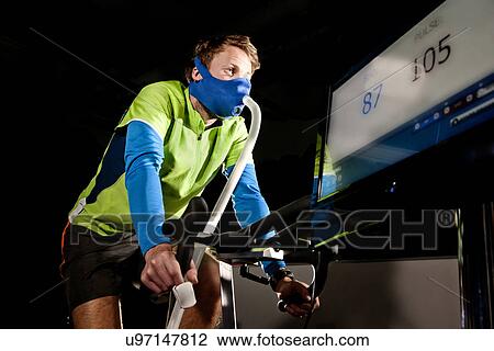 Download Young Man In Face Mask On Gym Exercise Cycle In Altitude Centre Stock Image U97147812 Fotosearch Yellowimages Mockups