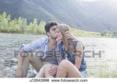 Young man kissing girlfriend on Toce riverbank, Piemonte, Italy View Large Photo Image Stock Photo - Young man kissing girlfriend on Toce riverbank, Piemonte, Italy. Fotosearch
