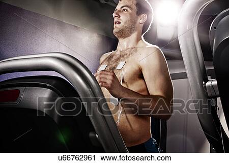 Stock Image - Young man with heart rate monitor on gym treadmill in altitude centre. Fotosearch
