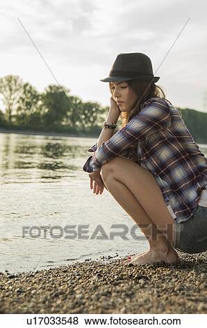 Young woman crouching by lake View Large Photo Image Stock Photo - Young woman crouching by lake. Fotosearch