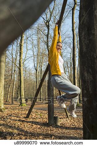 Young woman dangling from pole on forest assault course View Large Photo Image Stock Image - Young woman dangling from pole on forest assault course. Fotosearch