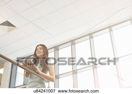 Young woman holding digital tablet, low angle View Large Photo Image Stock Photo - Young woman holding digital tablet, low angle. Fotosearch