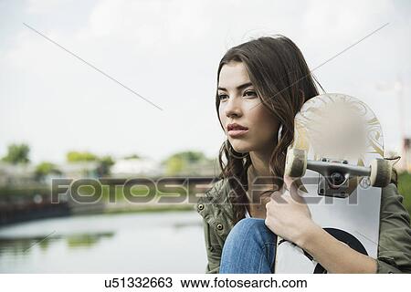 Young woman holding skateboard View Large Photo Image Stock Image - Young woman holding skateboard. Fotosearch