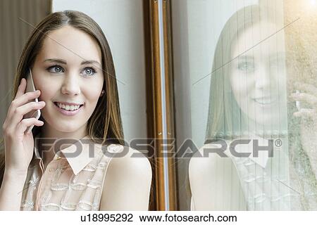 Young woman in cafe using smartphone and looking out of window View Large Photo Image Stock Image - Young woman in cafe using smartphone and looking out of window. Fotosearch