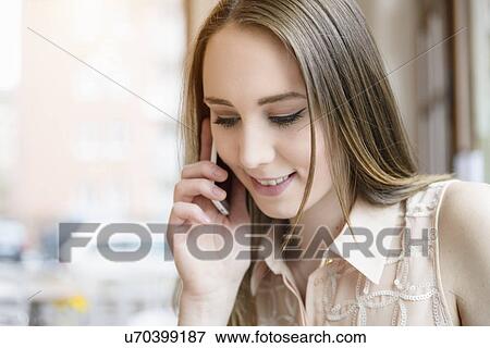 Stock Photo - Young woman in cafe using smartphone. Fotosearch