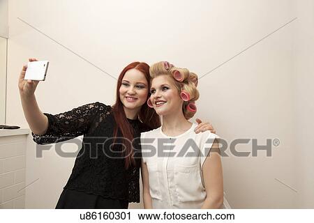 Young woman in curlers and friend taking selfie View Large Photo Image Stock Image - Young woman in curlers and friend taking selfie. Fotosearch