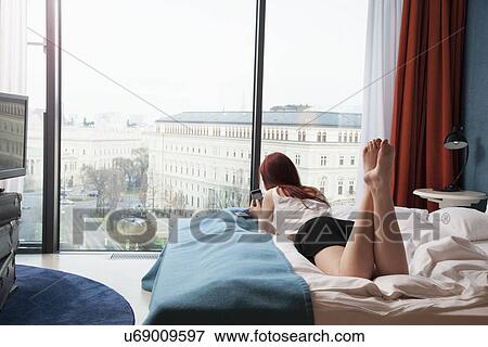 Young woman in hotel room overlooking street View Large Photo Image Stock Photo - Young woman in hotel room overlooking street. Fotosearch