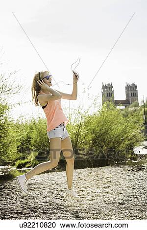 Young woman in park dancing whilst listening to headphones View Large Photo Image Stock Image - Young woman in park dancing whilst listening to headphones. Fotosearch