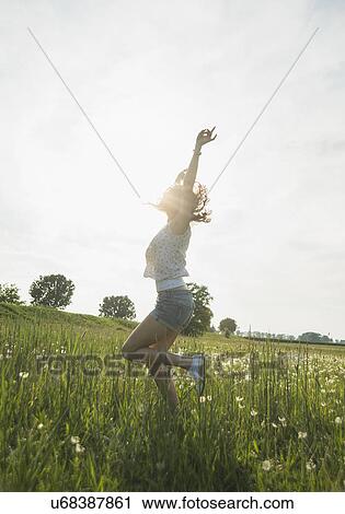 Young woman jumping in field View Large Photo Image Stock Image - Young woman jumping in field. Fotosearch