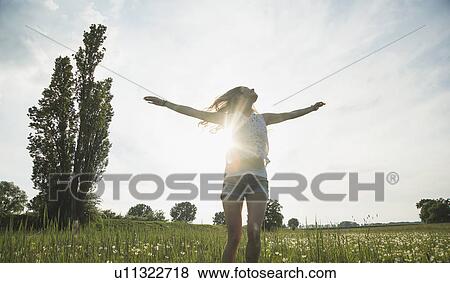 Stock Photo - Young woman jumping in field. Fotosearch