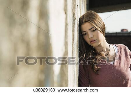Young woman leaning against wall View Large Photo Image Stock Image - Young woman leaning against wall. Fotosearch