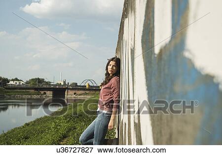 Young woman leaning against wall View Large Photo Image Stock Photo - Young woman leaning against wall. Fotosearch