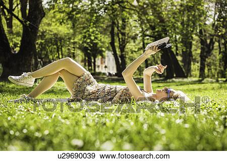 Young woman lying in forest taking selfie on digital tablet View Large Photo Image Stock Photo - Young woman lying in forest taking selfie on digital tablet. Fotosearch