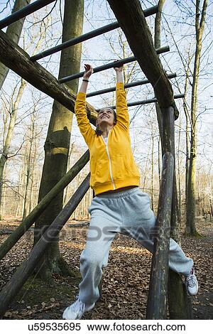 Young woman on climbing frame on assault course in forest View Large Photo Image Stock Photography - Young woman on climbing frame on assault course in forest. Fotosearch