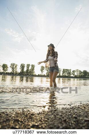 Stock Photo - Young woman paddling in lake. Fotosearch