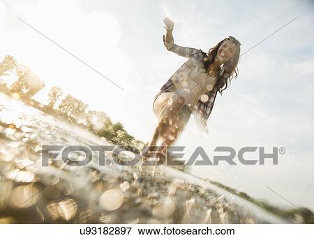 Stock Photo - Young woman paddling in lake. Fotosearch