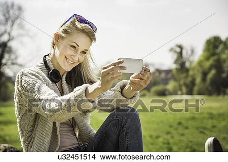 Picture - Young woman posing for self portrait in park. Fotosearch