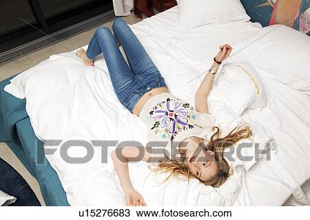 Young woman resting on bed View Large Photo Image Stock Image - Young woman resting on bed. Fotosearch