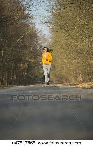 Young woman running on forest road View Large Photo Image Stock Photography - Young woman running on forest road. Fotosearch