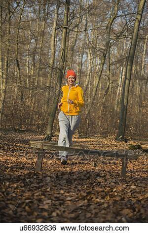 Young woman running toward fence on assault course in forest View Large Photo Image Stock Photograph - Young woman running toward fence on assault course in forest. Fotosearch