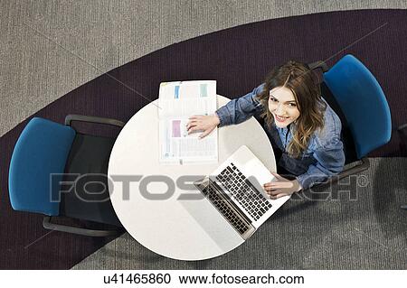 Young woman sitting at table using laptop, high angle View Large Photo Image Stock Image - Young woman sitting at table using laptop, high angle. Fotosearch