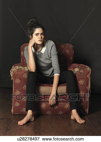 Stock Photo - Young woman sitting in armchair. Fotosearch