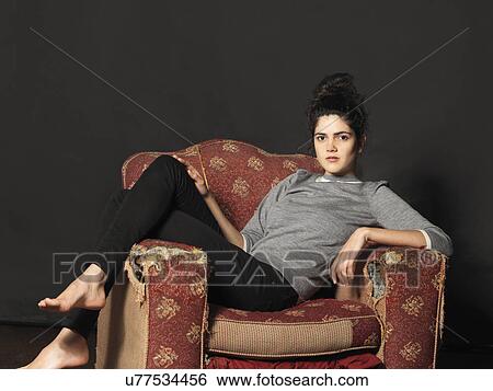 Stock Photograph - Young woman sitting in armchair. Fotosearch