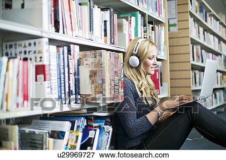 Young woman sitting on floor in library using laptop View Large Photo Image Stock Photo - Young woman sitting on floor in library using laptop. Fotosearch