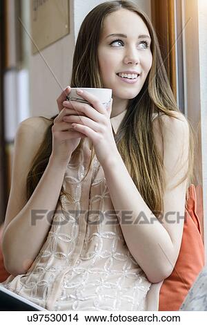 Young woman sitting with coffee in cafe View Large Photo Image Picture - Young woman sitting with coffee in cafe. Fotosearch