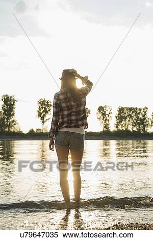 Young woman standing by lake View Large Photo Image Stock Photography - Young woman standing by lake. Fotosearch