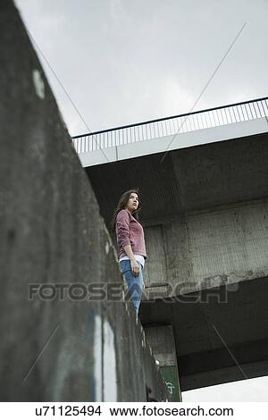 Young woman standing on wall, low angle View Large Photo Image Picture - Young woman standing on wall, low angle. Fotosearch