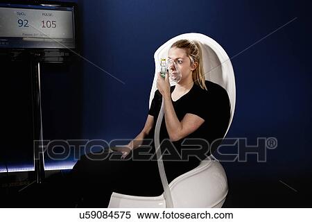 Stock Photography - Young woman using face mask in gym altitude centre. Fotosearch