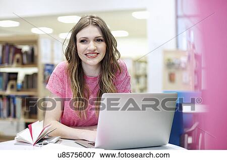 Young woman using laptop in library View Large Photo Image Stock Photo - Young woman using laptop in library. Fotosearch