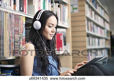 Young woman wearing headphones using digital tablet View Large Photo Image Stock Photography - Young woman wearing headphones using digital tablet. Fotosearch