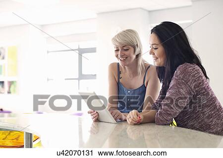 Stock Image - Young women using digital tablet. Fotosearch