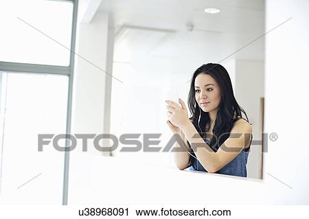 Stock Image - Young women using mp3 player. Fotosearch