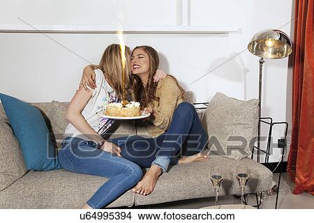 Young women with cake hugging on couch View Large Photo Image Picture - Young women with cake hugging on couch. Fotosearch