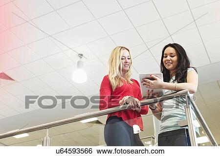 Stock Photograph - Young women with digital tablet, low angle. Fotosearch