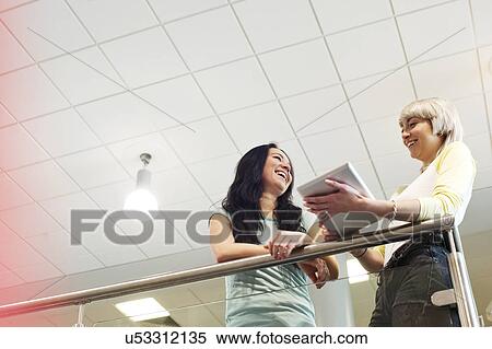 Stock Photography - Young women with digital tablet, low angle. Fotosearch