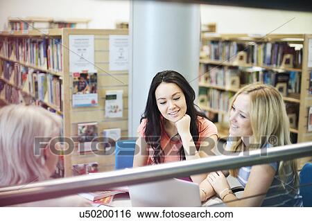 Stock Photograph - Young women working in library. Fotosearch