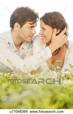 Affectionate man touching woman while looking at her on grass View Large Photo Image Picture - Affectionate man touching woman while looking at her on grass. Fotosearch