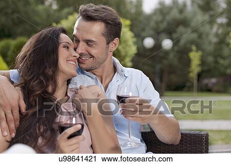 Affectionate young couple having red wine in park View Large Photo Image Stock Image - Affectionate young couple having red wine in park. Fotosearch