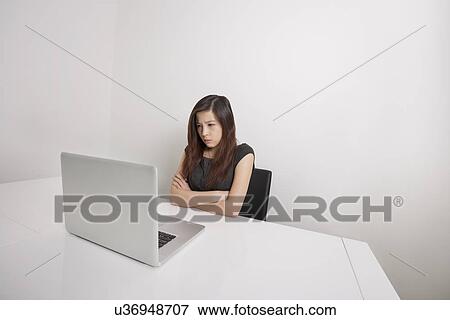 Angry young businesswoman with arms crossed looking at laptop in office View Large Photo Image Stock Photo - Angry young businesswoman with arms crossed looking at laptop in office. Fotosearch
